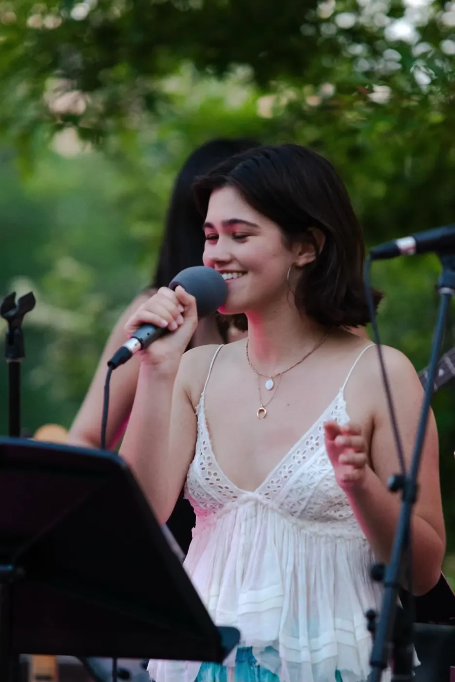 Julia Lebow singing into a microphone outdoors.